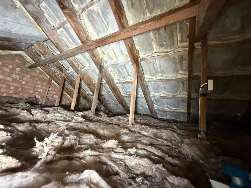 Old, flattened and dirty loft insulation between joists