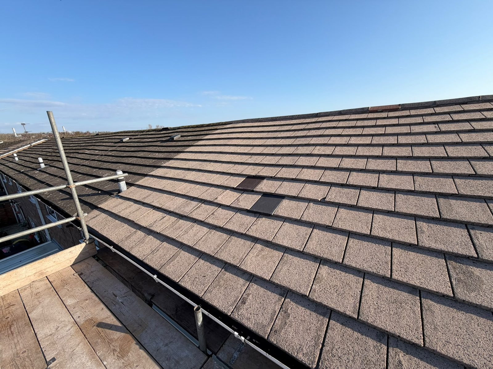 A retiled roof seen along the slope from the scaffold boards