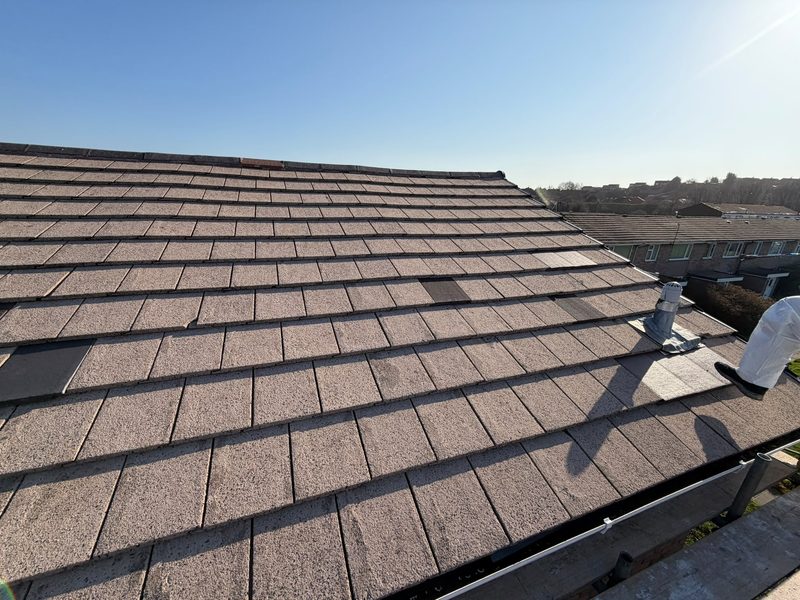 New concrete tiles running up to a re-bedded ridge, houses beyond